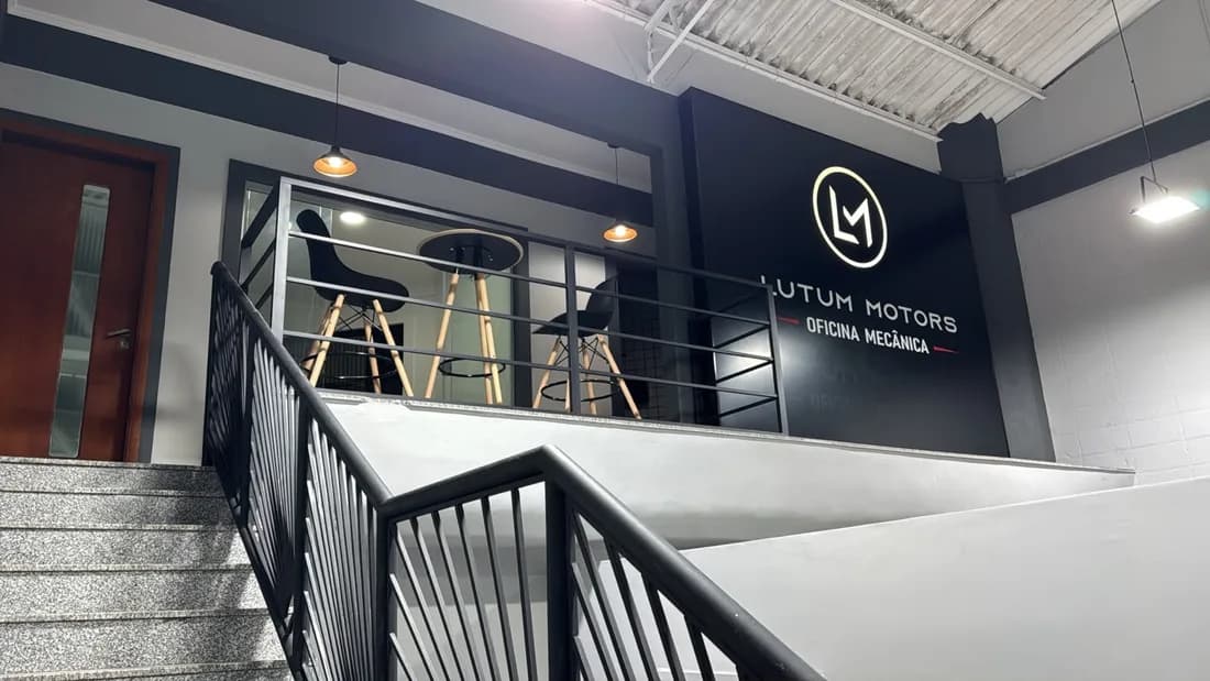 Área de espera no mezanino, com a marca Lutum Motors na parede